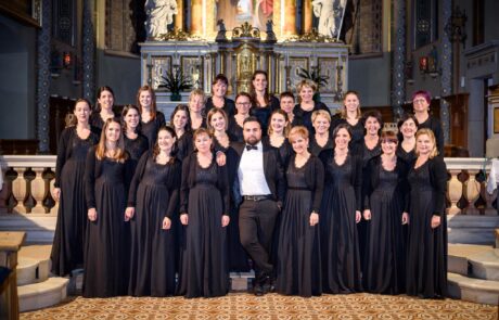 Chorale de femmes en concert dans une église ornée d'or et d'architecture classique.